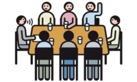 Mehrere Personen sitzen an einem Tisch. Die Personen unterhalten sich.